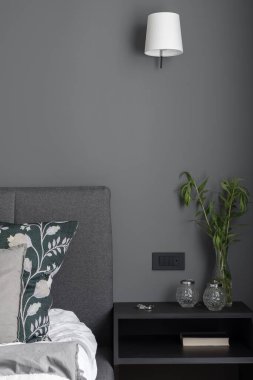 Şık yatak odası, rahat yatak odası ve sade, siyah, beyaz lambanın altında güzel süslemeleri olan komodinli.