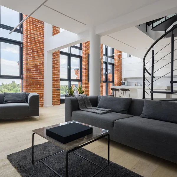 Simple and bright living room in stylish, two-floor loft apartment with amazing, big windows and red bricks on the walls
