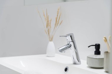 Klasik banyo lavabosundaki süslemeli gümüş musluğa yakın çekim.