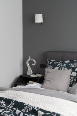 Şık yatak odası, rahat yatak odası, güzel çarşaflar, şık, siyah komodinli kitaplar ve dekorasyonlar.