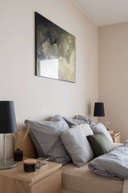 İki odalı rahat bir yatak, ahşap komodinli basit siyah lambalar ve parlak yatak odasında süslemeler.