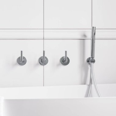 Zarif ve süslü, gümüş duvara monte edilmiş banyo musluğu, duş ve duvarda beyaz fayanslar var.