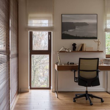 Zarif ve rahat ofis odasında ahşap panjurlu pencere duvarları, ahşap zemin, ahşap masa ve rahat sandalye olan ahşap bir dekor.