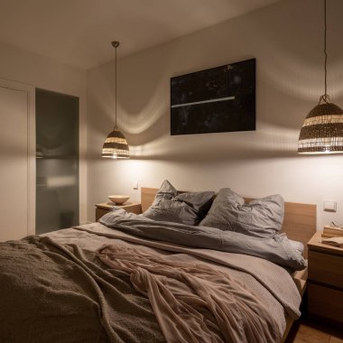 Büyük yataklı rahat ve hoş bir yatak odası, iki ahşap komodin ve güzel ışıklandırmalı iki rattan lamba.