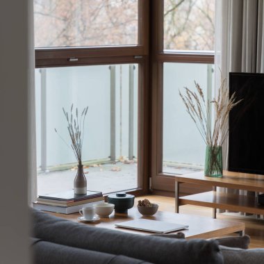 Şık, ahşap sehpaya yakın çekim. Oturma odasında güzel dekorasyonlar ve büyük pencereli kitaplar var.