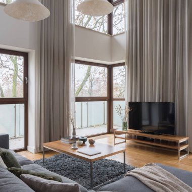 Çok sayıda penceresi, şık perdeleri, rahat kanepesi ve sehpası, büyük televizyon ekranı ve güzel dekorasyonları olan olağanüstü ve ferah bir oturma odası.