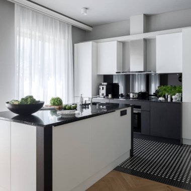 Beyaz ve siyah mobilyalı lüks mutfak, beyaz perdelerin arkasındaki büyük pencere ve lavabolu işlevsel mutfak adası.