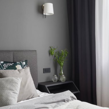 Büyük yatak ve perdeleri olan basit ve rahat bir yatak odasında kristal süslemeli siyah komodin.