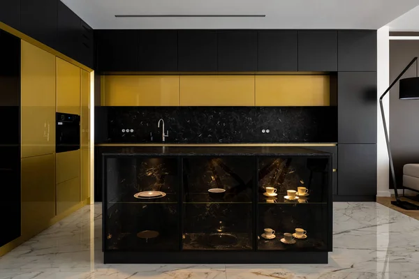 Exclusive kitchen with gold and black furniture, big kitchen island and elegant marble floor tiles