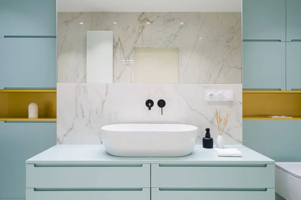 现代设计的浴室 蓝色的橱柜和抽屉的箱子下面 时尚的白色 椭圆形洗脸盆与黑色水龙头和金架子 — 图库照片