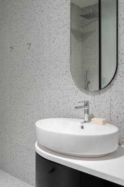 Modern banyo oval lavabo, ayna ve dolap ve şık terrazzo fayanslarıyla