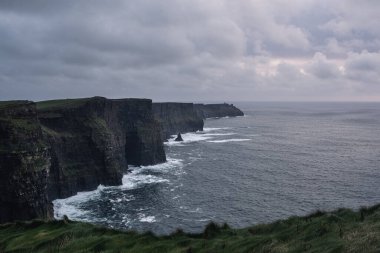 Muhteşem Moher Kayalıkları ve dalgalı deniz üzerinde kara bulutlar, İrlanda
