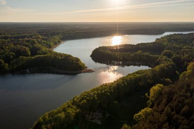 Yeşil ormanda, geniş nehrin üzerinde inanılmaz bir günbatımı, drone manzarası.