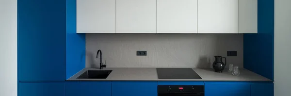 全景由简单 现代和小厨房组成 配有蓝白橱柜 灰色台面 背面水花和黑色水槽 — 图库照片