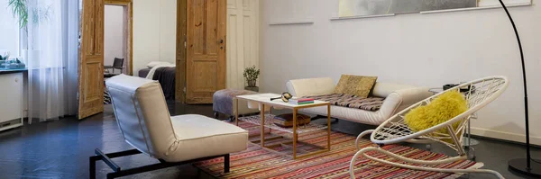 Panorama of vintage and eccentric living room with old, wooden doors, stylish furniture and artistic decorations