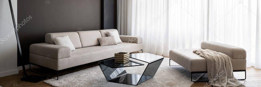 Panorama of stylish living room with elegant, big beige couch and seat, modern coffee table and window behind white curtains