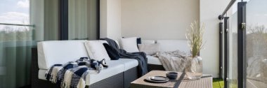 Güzel bir balkon panoraması, rattan köşeli kanepe ve kahve masası.