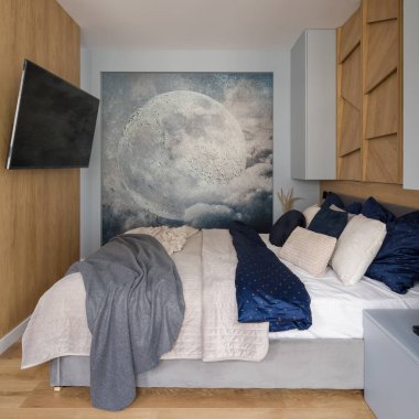 Ay posterli küçük yatak odası, ahşap duvarlı televizyon ve büyük, rahat ve şık dekore edilmiş yatak.