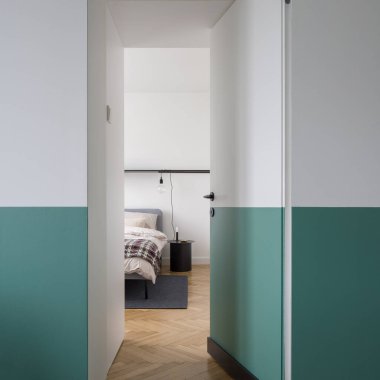 Modern beyaz ve yeşil kapılar ahşap zeminli ve rahat yataklı şık yatak odalarına açıktır.