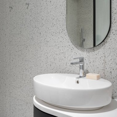 Modern banyodaki küçük ve oval lavaboya yakın çekim, modern terrazzo fayanslı oval ayna.