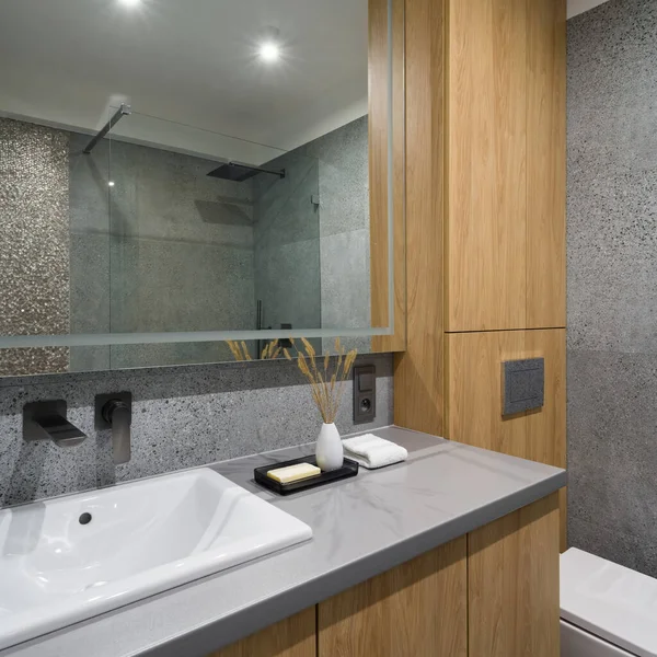 现代化的浴室 配有灰色梯形瓷砖 洗脸盆上方的大镜子 配有灰色台面和木制橱柜 — 图库照片