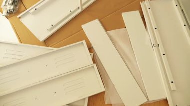 Ahşap zemine mobilya montaj aletleri ve donanım döşenmiş. DIY kurulumdan önce gösterilen vidalar, parantezler, çekmece slaytları, paneller ve tornavidalar. Ev geliştirme görselleri için ideal