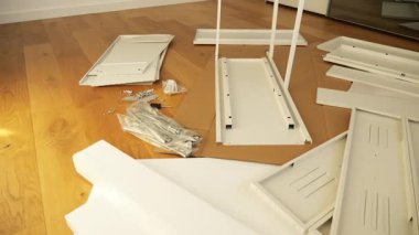 Ahşap zemine mobilya montaj aletleri ve donanım döşenmiş. DIY kurulumdan önce gösterilen vidalar, parantezler, çekmece slaytları, paneller ve tornavidalar. Ev geliştirme görselleri için ideal