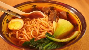 Geleneksel ramen kasesine yakın çekim. Erişte, yumurta, et, Çin mantısı ve koyu et suyu. Tahta kaşık ve yemek çubukları üstte. Asya mutfağı, yemek tasarımı ya da restoran görselleri için mükemmel.