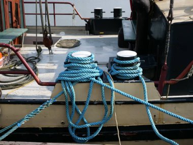 Rıhtıma yanaşmış bir teknede beyaz kalınlıklarla çevrili denizcilik halatlarının yakın çekimi. Denizcilik ekipmanları, güverte detayları ve deniz, liman ya da tekne görüntüleri için mükemmel bir arka plan.