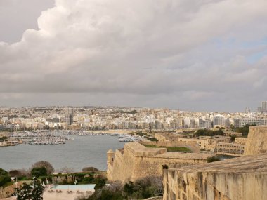 Sayısız beyaz binaları, modern bir gökdelenleri ve palmiye ağaçları ve ön planda bir bahçesi bulunan bir yat marinası olan yüksek açılı bir sahil kenti ve liman manzarası..