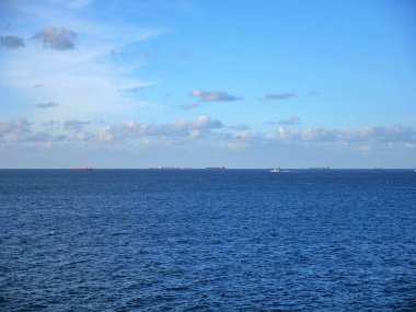 Ufuktaki çoklu kargo gemileri açık okyanus mavi gökyüzünün altında bulutlu