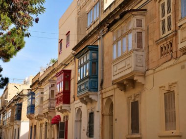 Geleneksel renkli Malta ahşap balkonları Malta 'daki tarihi kireç taşlarının üzerinde. Otantik Akdeniz sokak manzaralı mimarisi.