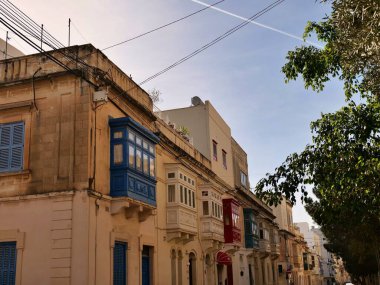 Geleneksel mavi Malta ahşap balkonu Gallarija Malta 'da tarihi bir kireçtaşı yapı cephesinde. Mavi gökyüzü altında otantik Akdeniz mimari ayrıntıları.
