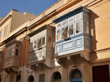 Geleneksel renkli Malta ahşap balkonları Birgu Malta 'nın tarihi kireçtaşı cephesinde gallarija yapıyor. Otantik Akdeniz sokak manzaralı mimarisi