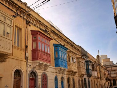 Geleneksel renkli Malta ahşap balkonları Birgu Malta 'nın tarihi kireçtaşı cephesinde gallarija yapıyor. Otantik Akdeniz sokak manzaralı mimarisi