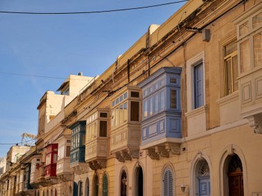 Geleneksel renkli Malta ahşap balkonları Birgu Malta 'nın tarihi kireçtaşı cephesinde gallarija yapıyor. Otantik Akdeniz sokak manzaralı mimarisi