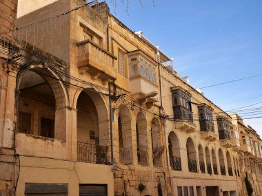 Geleneksel Malta kireçtaşı ev cephesi kemerli zemin katı ve renkli ahşap gallarija balkonları Malta 'da. Otantik Akdeniz sokak mimarisi.