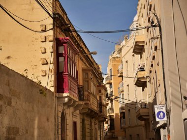 Geleneksel kırmızı Malta ahşap balkon gallarija Malta 'daki tarihi kireçtaşı yapı cephesinde. Altın saat ışığında otantik Akdeniz mimari ayrıntıları.