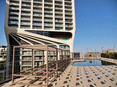 Modern çatı havuzu terası. Minimalist güneş şezlongları, geometrik fayanslar ve fütürist gökdelen mimarisini yansıtan bir yüzme havuzu olan lüks bir otel. Üst düzey gayrimenkul ve seyahat fotoğrafçılığı.