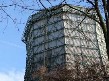 Endüstriyel soğutma kulesinin yakın çekimi. Metal yapı iskelesi. Mavi gökyüzüne ve çıplak dallara karşı kıvrımlı kaplamalı büyük soğutma istasyonu. Endüstriyel mimari detaylı enerji üretim tesisi ve mühendisliği