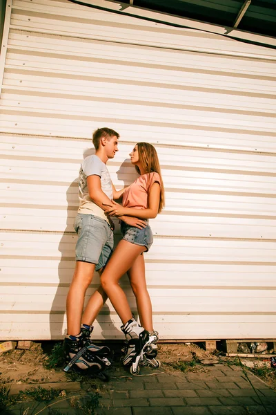 Закохана пара на роликах біля білої стіни на вулиці — стокове фото