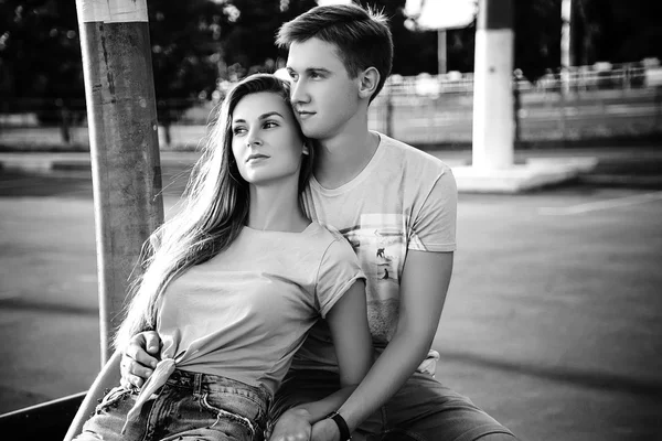 Loving couple sitting at the street on the sunset. Black and whi — Stock Photo, Image