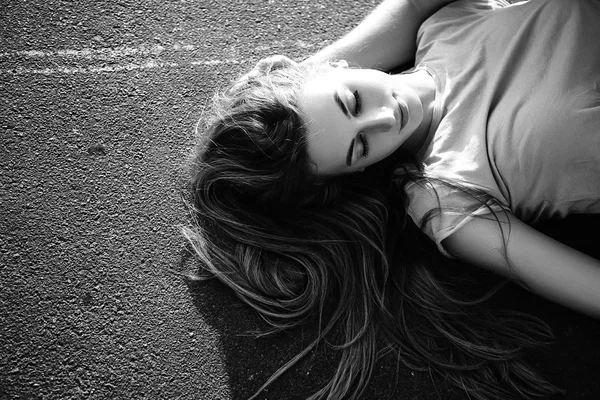 Mooi meisje liggend op het asfalt. Zwart-wit — Stockfoto