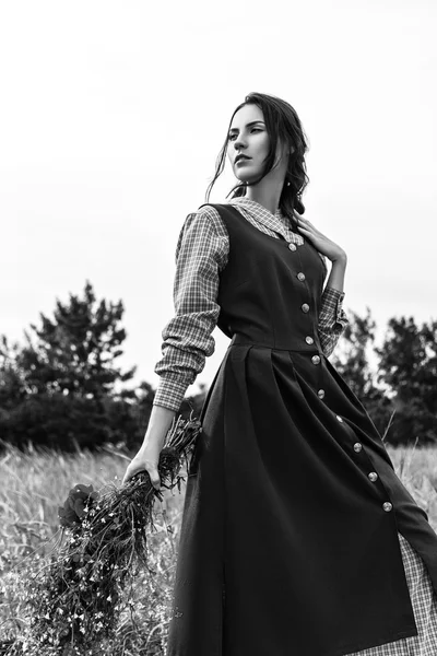Outdoor Portret van een mooie brunette vrouw in blauwe jurk in het veld. Zwart-wit foto — Stockfoto