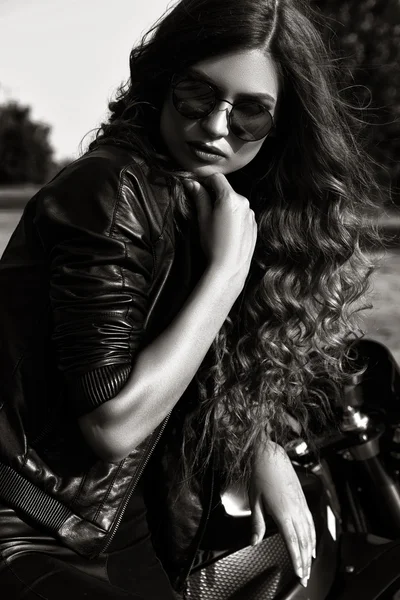 Sexuell Biker kvinna klädd i svart skinnjacka med sin sport motorcykel på en motorväg. Skönhet, mode. Äventyr och frihet. Svartvitt foto — Stockfoto
