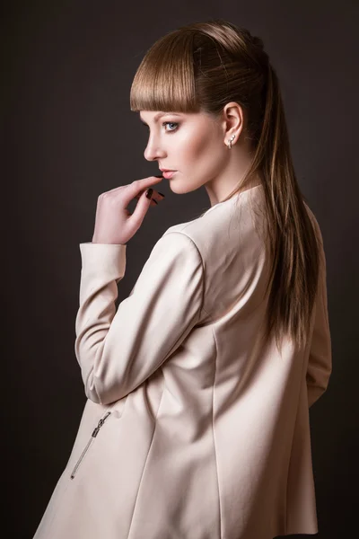 Modelo de mujer hermosa posando en simple elegante en un traje de luz en el estudio sobre fondo negro — Foto de Stock