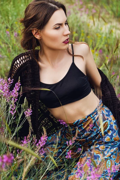 Mode outdoor portret van een mooie brunette vrouw met bloemen in haar in het veld — Stockfoto