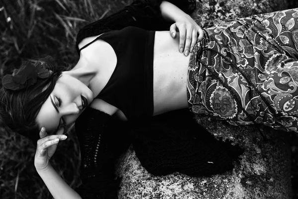 Fashion outdoor portrait of a beautiful brunette woman with flowers in hair in the field. Black and white photo — Stock Photo, Image