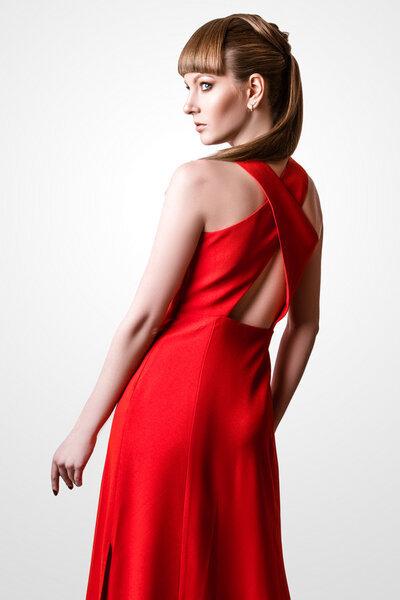 красивая женщина модель позирует в простом элегантном красном платье в студии на белом фоне
