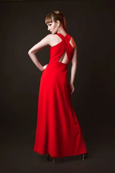 Schöne Frau Modell posiert in einfachen eleganten roten Kleid im Studio auf schwarzem Hintergrund — Stockfoto